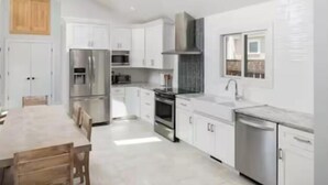 Una cocina moderna con armarios blancos, electrodomésticos de acero inoxidable y una mesa de comedor de madera.