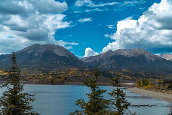 A mountainous landscape with a lake, trees, and a clear sky.