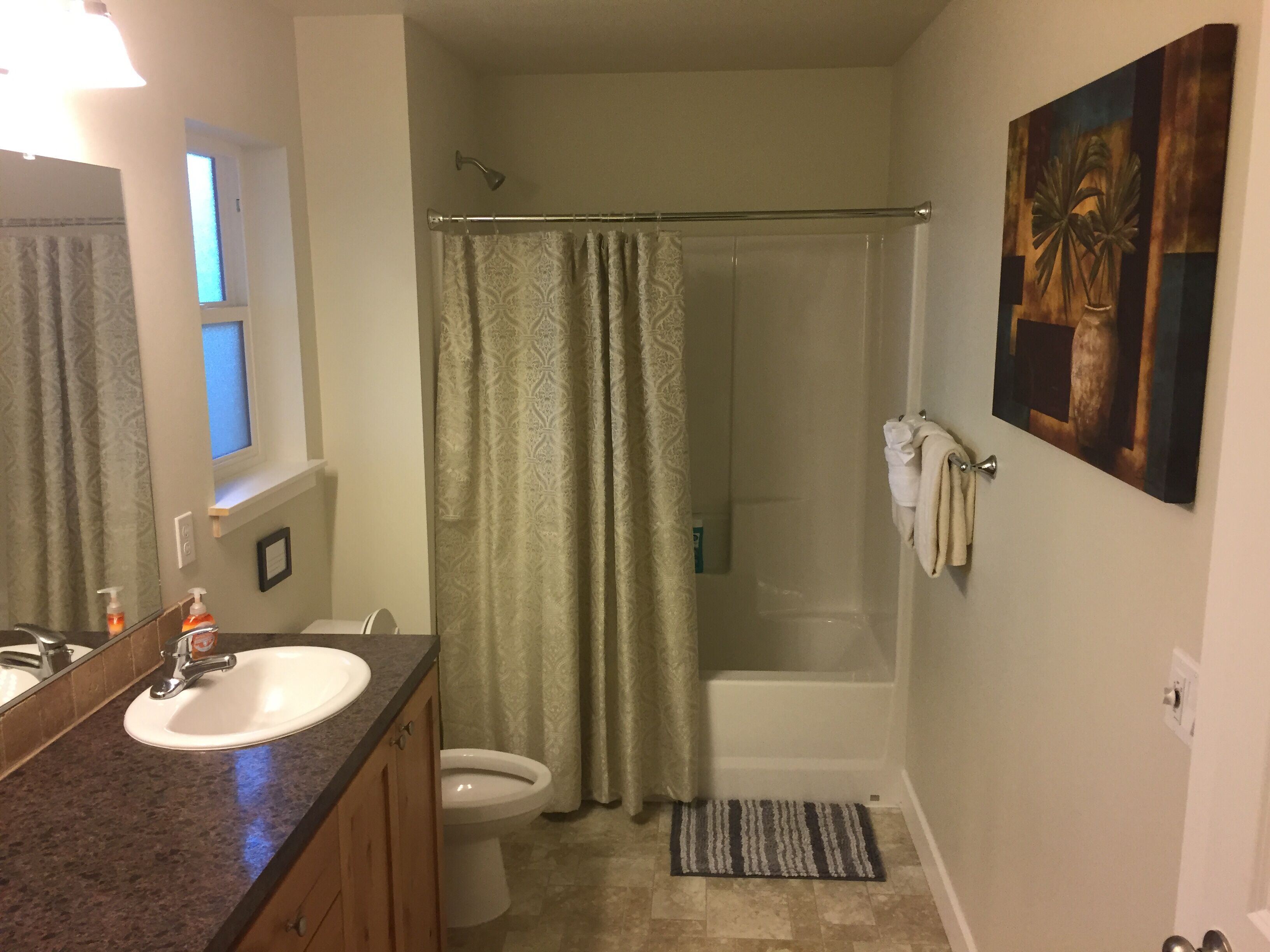 A bathroom with a sink, toilet, shower, and a towel rack.