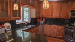 A kitchen with wooden cabinets, a granite countertop, stainless steel appliances, and a window providing natural light.