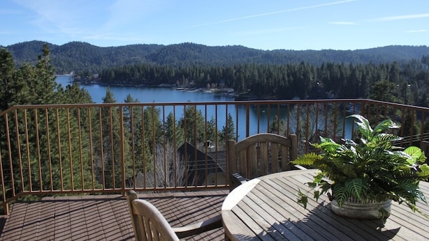 A wooden deck with a view of a lake and forested hills.