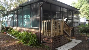 Een overdekt buitengebied met een houten terras en een veranda met hor.