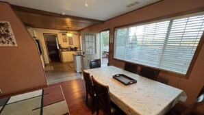 A dining area with a table, chairs, and a window with blinds. - 2bd2bth CABIN with  WIFI,  HotTub,  Full Kitchen, smart tv/ Book1week get 20%off (Big Bear Lake)