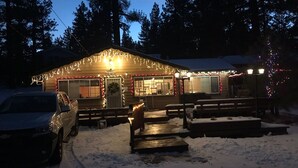 A cabin with a wooden exterior, a covered porch, and a snow-covered ground. - 2bd2bth CABIN with  WIFI,  HotTub,  Full Kitchen, smart tv/ Book1week get 20%off (Big Bear Lake)