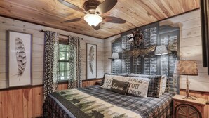 Un dormitorio acogedor con techo de madera, una cama con manta acolchada y un ventilador de techo.