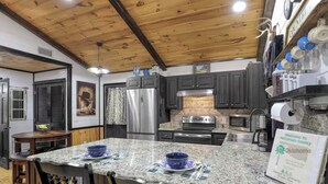 Una cocina con encimeras de granito, gabinetes oscuros, electrodomésticos de acero inoxidable y un cartel de bienvenida al condado de McCurtain, Oklahoma.