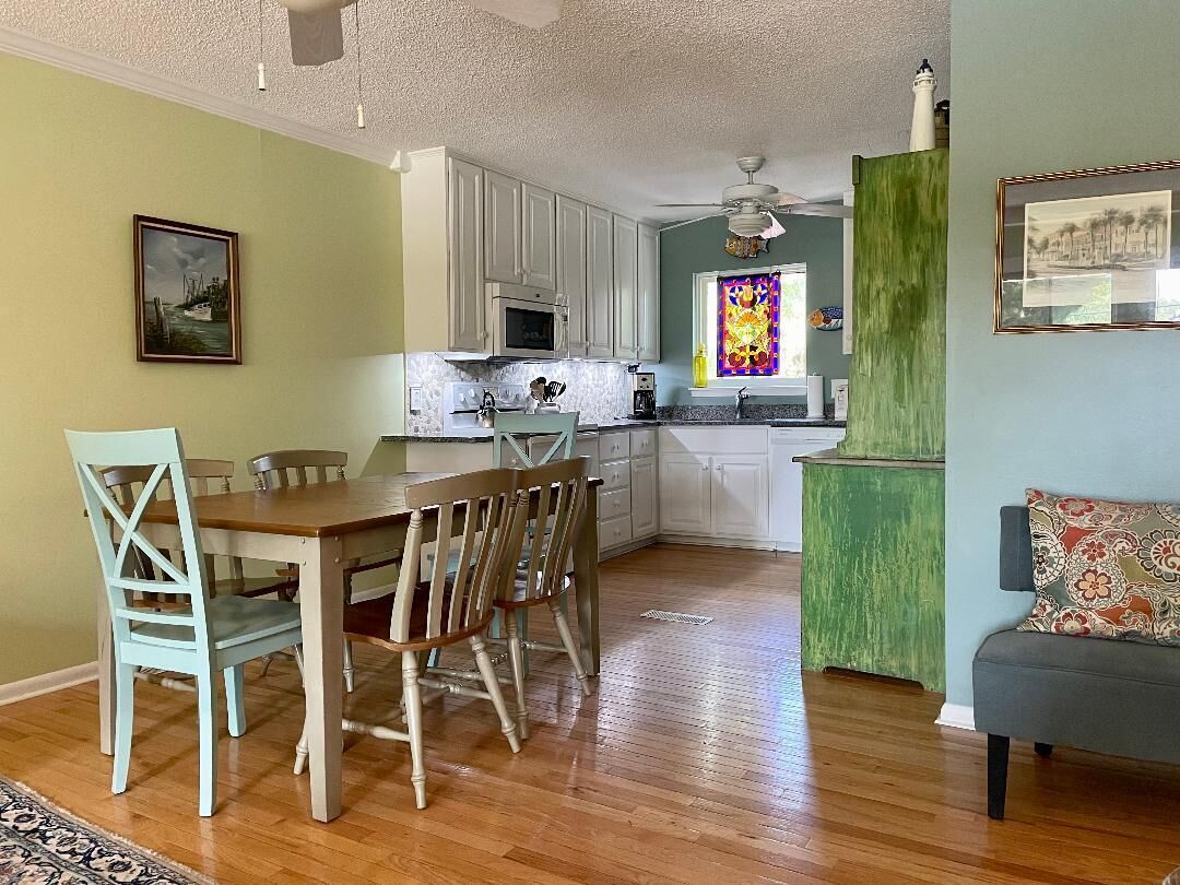 A compact kitchen with white cabinets, a dining table with chairs, and a green accent wall.