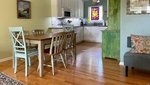 Una cocina compacta con armarios blancos, una mesa de comedor con sillas y una pared de acento verde.