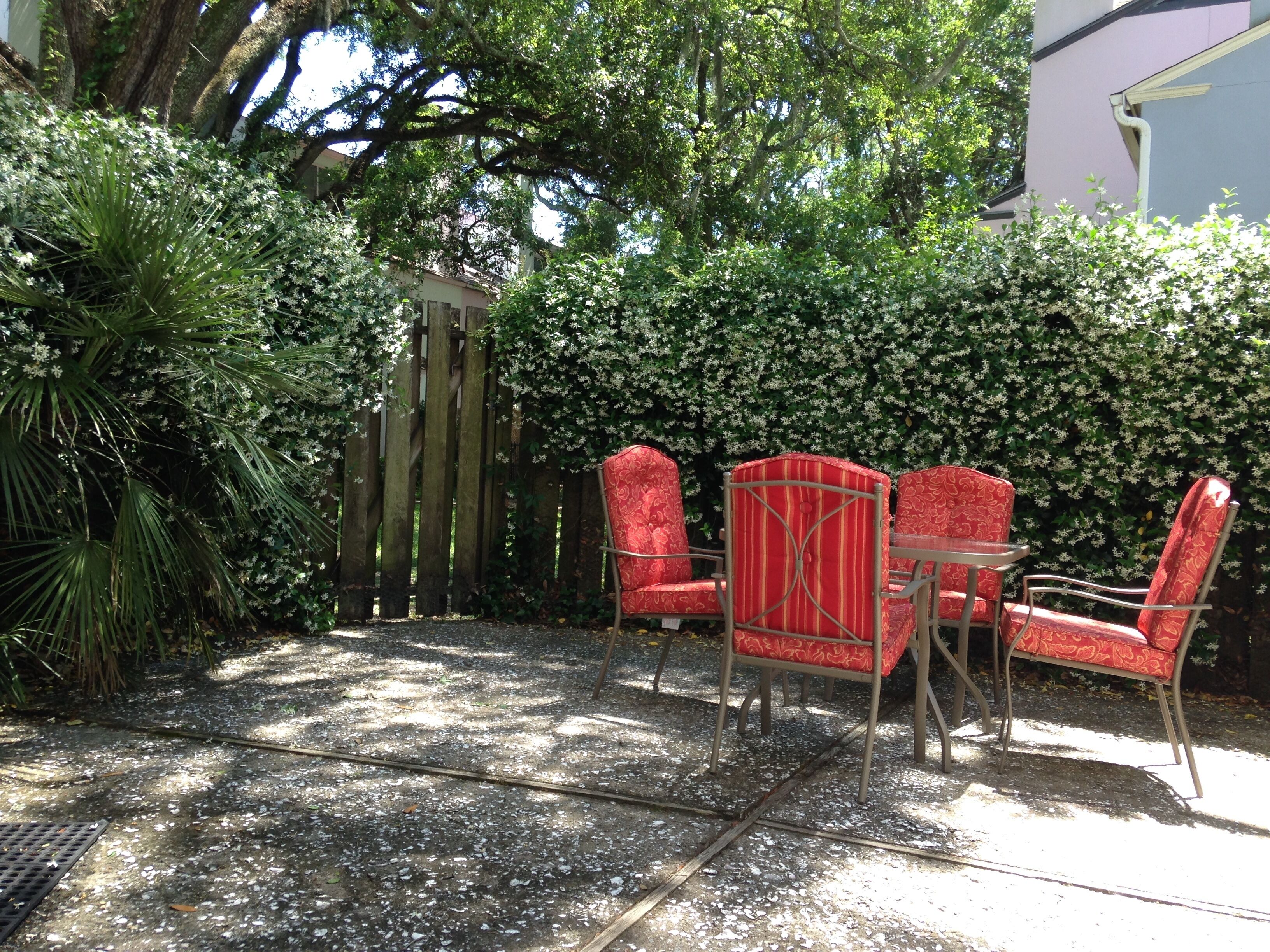 Une terrasse avec une clôture en bois, des chaises rouges et une table.