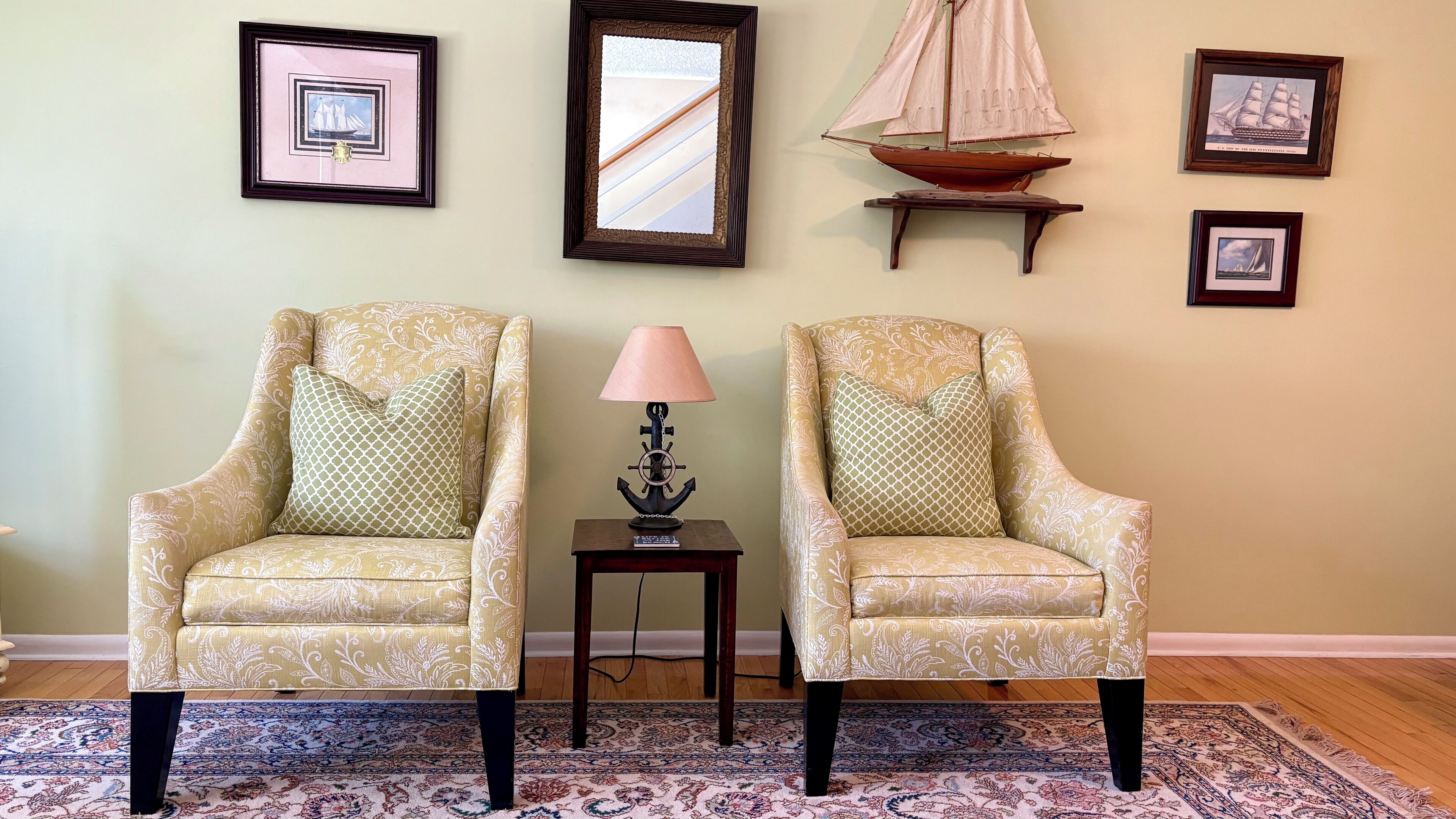 Deux fauteuils à motifs, placés face à face, avec une petite table et une lampe entre eux, le tout posé sur un tapis à motifs.