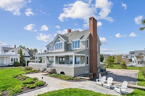 A two-story house with a porch, a chimney, and a well-maintained lawn. - Spectacular Oceanfront Beach House on Gooch's Beach (Kennebunk)