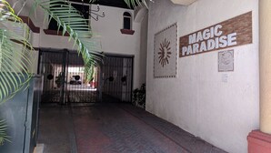 Un couloir orné d’une enseigne sur laquelle on peut lire « MAGIC PARADISE » et d’un motif représentant un soleil.