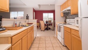 A modern kitchen with wooden cabinets, a dining area with a table and chairs, and a view of the outside through a window. - Beautiful pool great location near to the beach. Special Prices for Nov and Dec! (Sarasota)