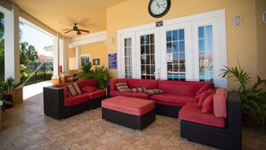 A covered outdoor seating area with a red sofa set, a clock, and a pool view. - Beautiful pool great location near to the beach. Special Prices for Nov and Dec! (Sarasota)