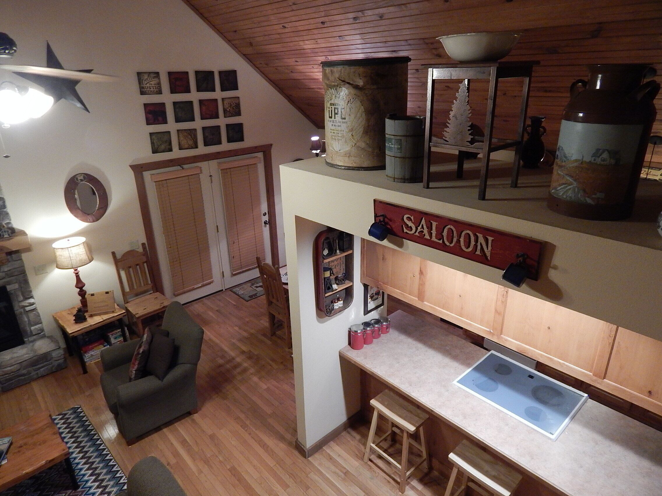 A rustic kitchen with wooden cabinets, a wooden ceiling, and a sign reading "SALOON".