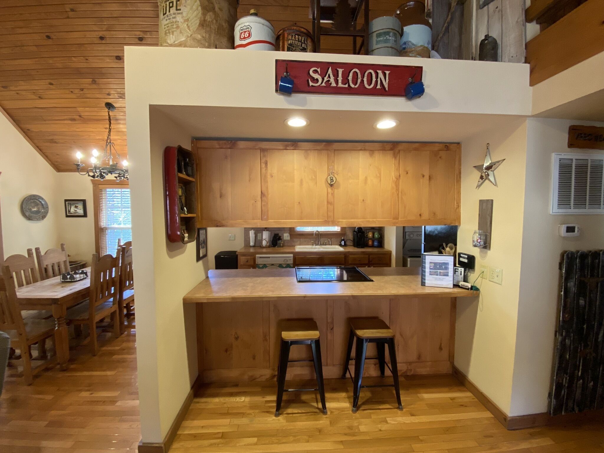 Una cocina con armarios de madera, una zona de bar con taburetes y una mesa de comedor con sillas.