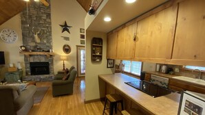 Un salón amplio con chimenea, una pared de piedra y techo de madera.