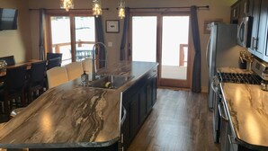 A modern kitchen with a marble island, stainless steel appliances, and pendant lighting.