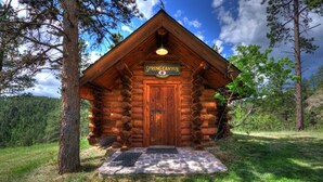 A log cabin with a sign reading "Spring Canyon School" and a wooden door.