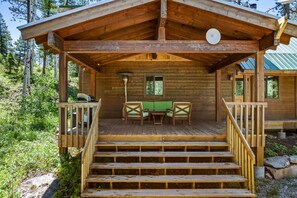 Une cabane en bois avec une véranda, une table et deux chaises.