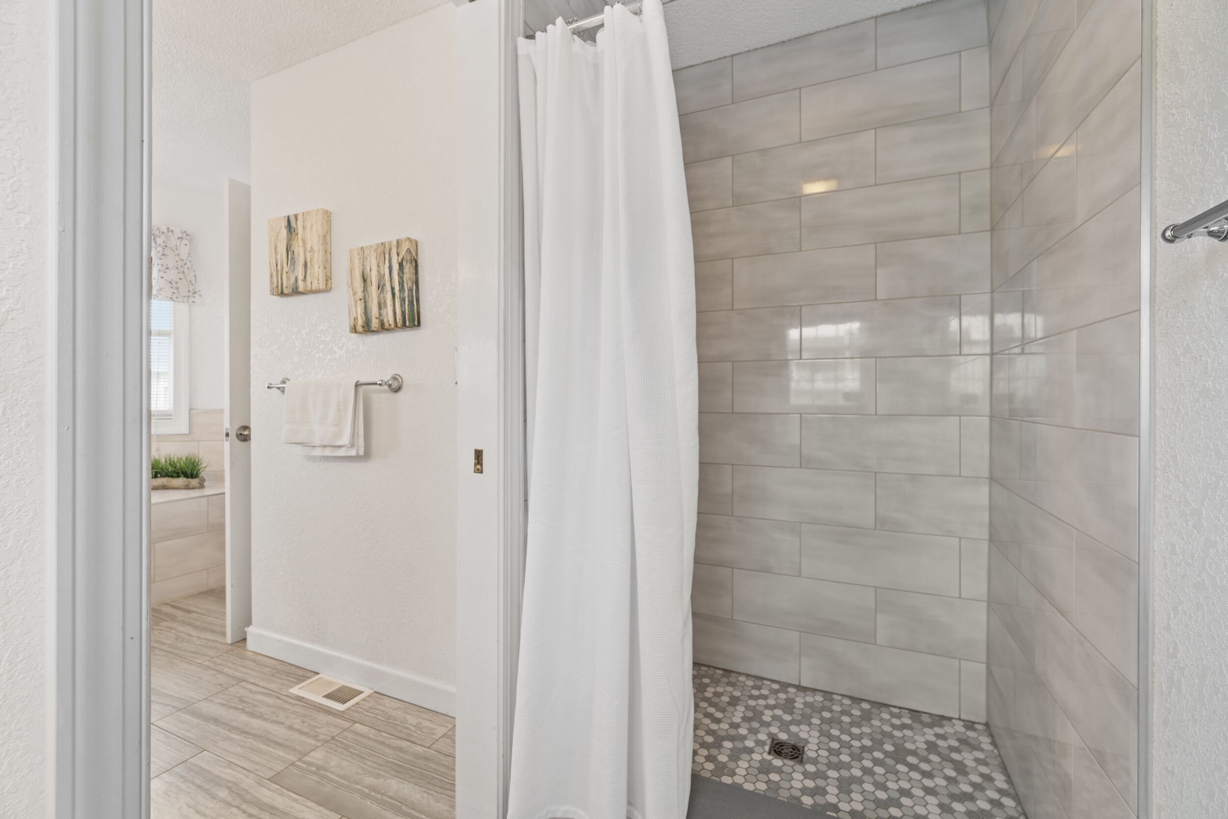 A modern bathroom with a shower, tiled walls, and a door with a towel hanging on it.