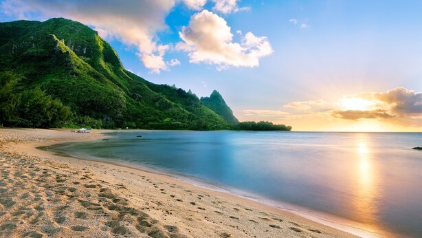 A beach with a mountain in the background and a clear sky.