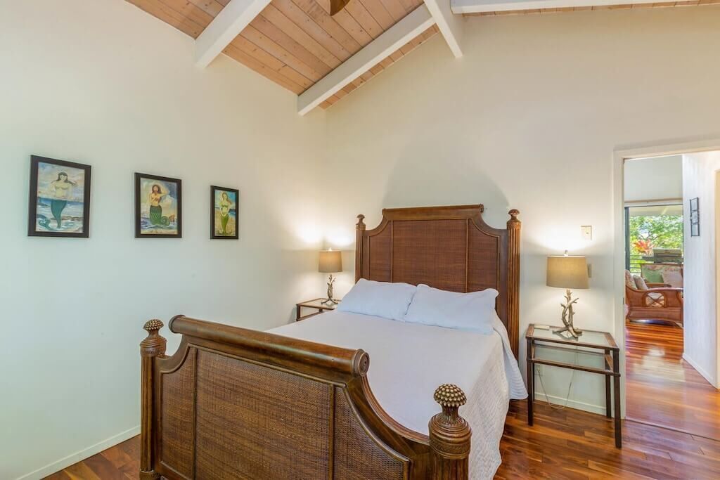 Een slaapkamer met een houten bed, twee nachtkastjes met lampen en drie ingelijste kunstwerken aan de muur.