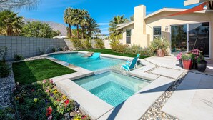 Un patio trasero con piscina, jacuzzi y zona de estar al aire libre con mobiliario.