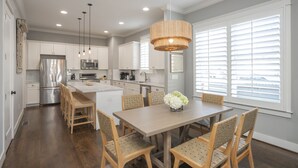 A modern kitchen with white cabinets, stainless steel appliances, and a dining area with a wooden table and chairs. - Downtown in 7min & Rooftop Deck! Gorgeous Stunning Nashville Home!  (Nashville)