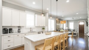A modern kitchen with white cabinets, a marble island, wooden chairs, and pendant lighting. - Downtown in 7min & Rooftop Deck! Gorgeous Stunning Nashville Home!  (Nashville)