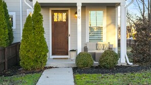 A two-story house with a front porch, a brown door, and a mailbox. - Downtown in 7min & Rooftop Deck! Gorgeous Stunning Nashville Home!  (Nashville)