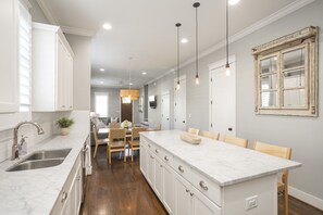 A modern kitchen with a central island, white cabinetry, and pendant lighting. - Downtown in 7min & Rooftop Deck! Gorgeous Stunning Nashville Home!  (Nashville)