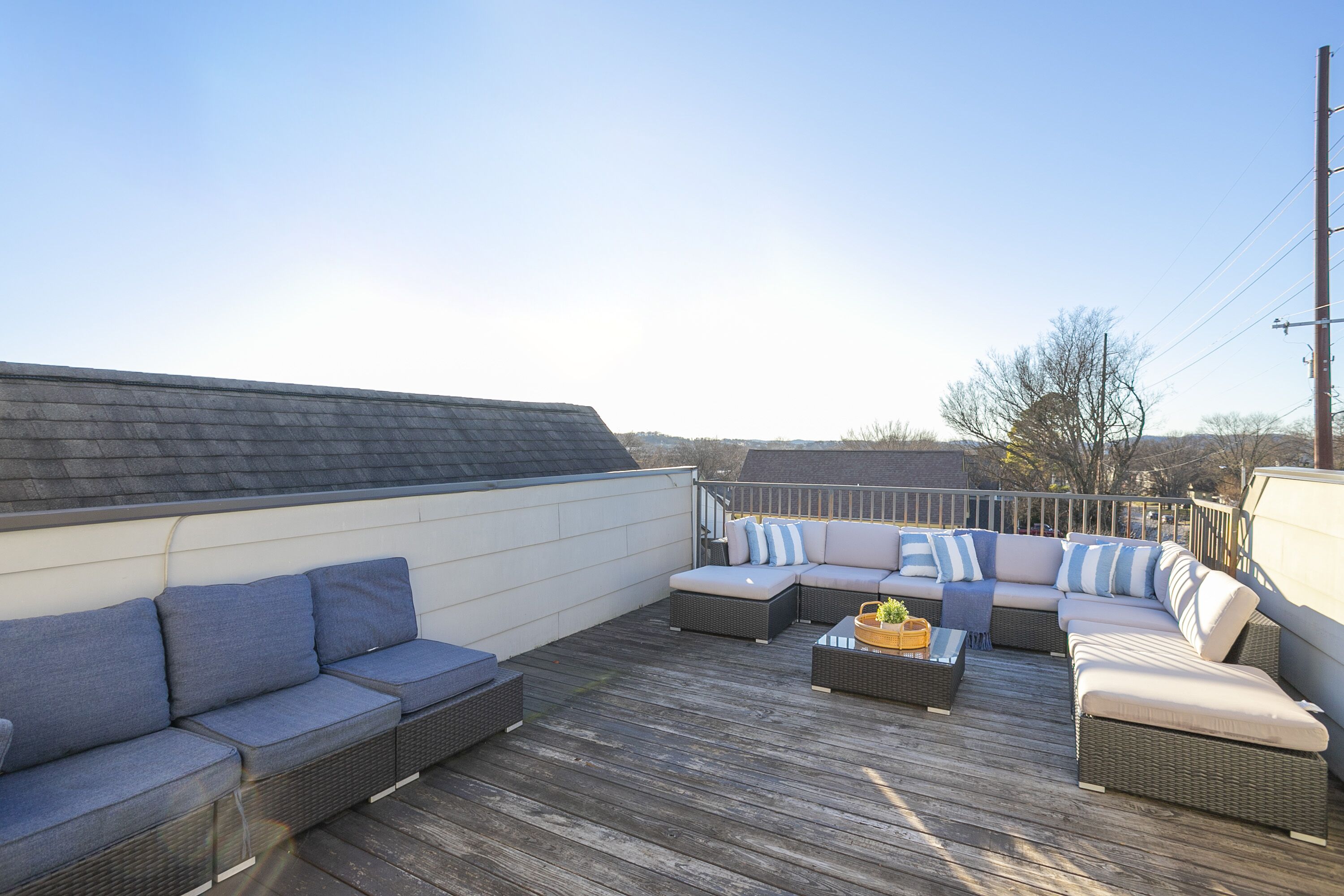 A rooftop patio with a sectional sofa, a small table, and a wicker chair.