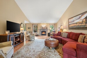 A living room with a fireplace, a television, and a large window. - Comfortable & Clean | 2 King Beds | Single Level (Dundee)