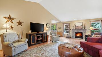 A living room with a fireplace, a television, and a large window.
