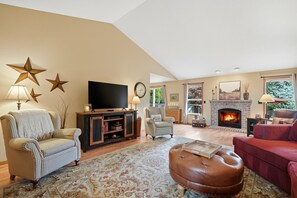 A living room with a fireplace, a television, and a large window. - Comfortable & Clean | 2 King Beds | Single Level (Dundee)