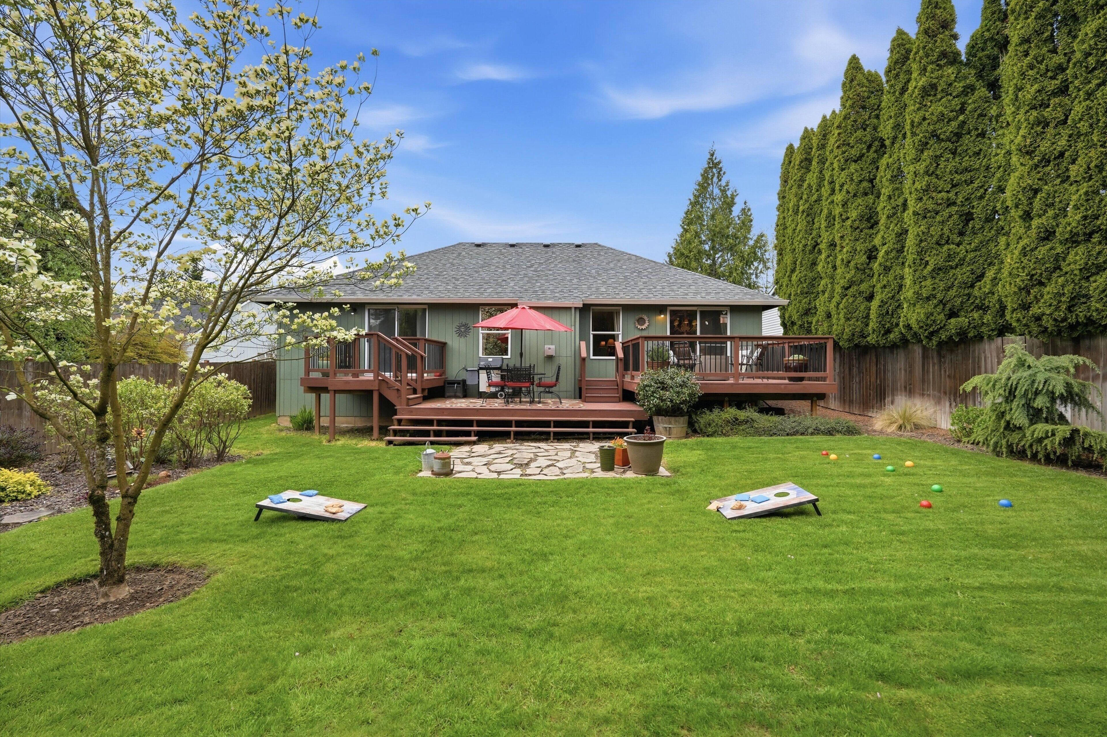 Een huis met een terras, een patio en een gazon met een tafel en stoelen.