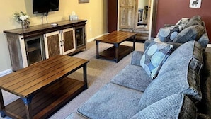 A living room with a sofa, two wooden tables, a TV, and a cabinet. - 5 Star Denali Park Spacious Family Home (Healy)