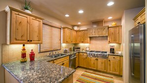 Una cucina moderna con mobili in legno, piani in granito, elettrodomestici in acciaio inossidabile e un tappeto colorato a righe.