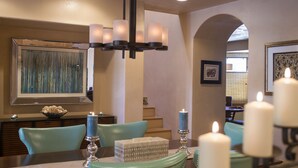 Zona pranzo con un lampadario, un quadro astratto incorniciato e candele sul tavolo.