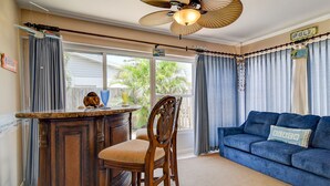 A room with a wooden bar, a blue sofa, and a ceiling fan.