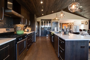 A modern kitchen with dark wood cabinets, stainless steel appliances, and a large island.
