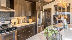 A modern kitchen with dark wood cabinets, stainless steel appliances, and pendant lighting. - 20 acres private ranch with Mountain View’s  (Bend)