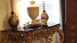 A wooden console table with ornate carvings, a vase, and a lamp.
