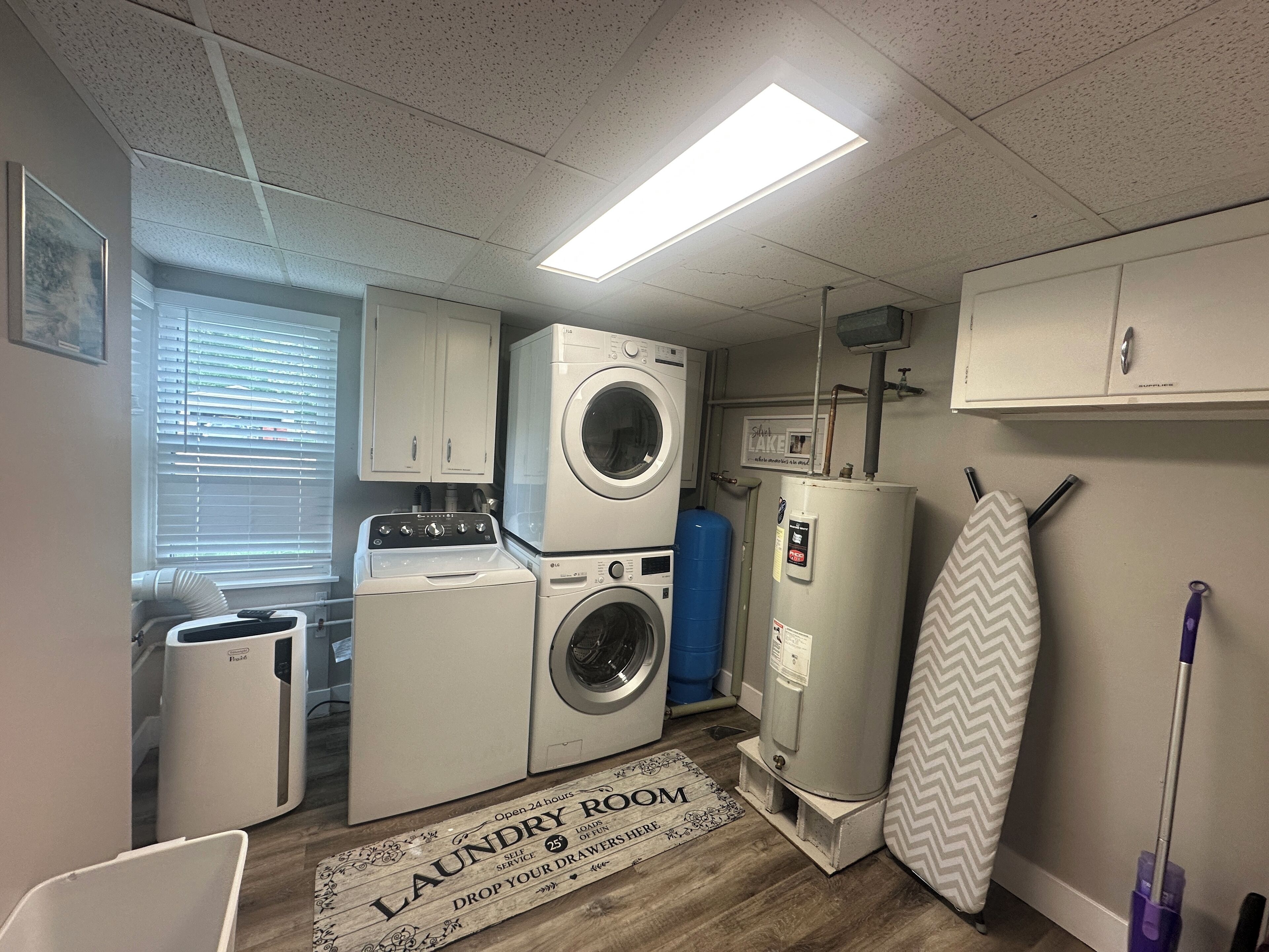 A laundry room with a washer and dryer, a water heater, and a drying rack.