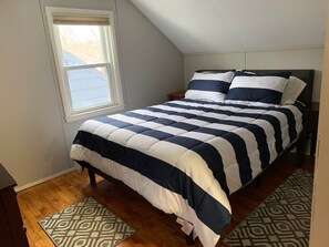 A bedroom with a bed, a window, and patterned rugs.