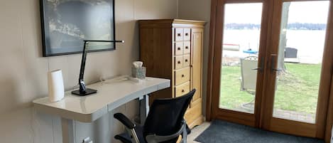 A home office with a desk, chair, and a view through a glass door.
