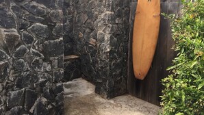 Eine Steinsäule mit einem Holzzaun und einem Surfbrett, das dagegen gelehnt ist.