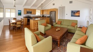 Ein großzügiger Wohnbereich mit einem Holzesstisch, grünen Sofas und einer Küche mit modernen Geräten.