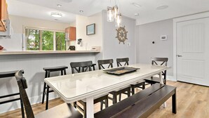 Une cuisine moderne dotée d’un grand îlot central, de meubles blancs et offrant une vue sur la verdure environnante.